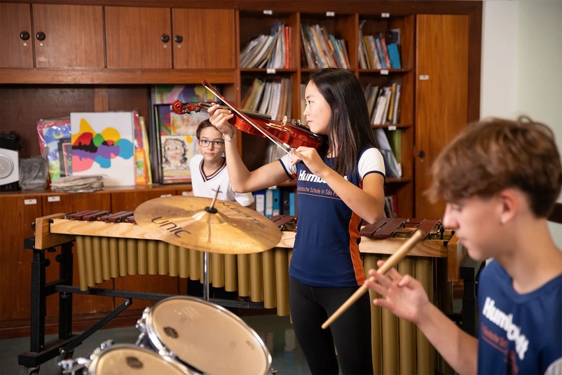 Alunos praticando com instrumentos musicais